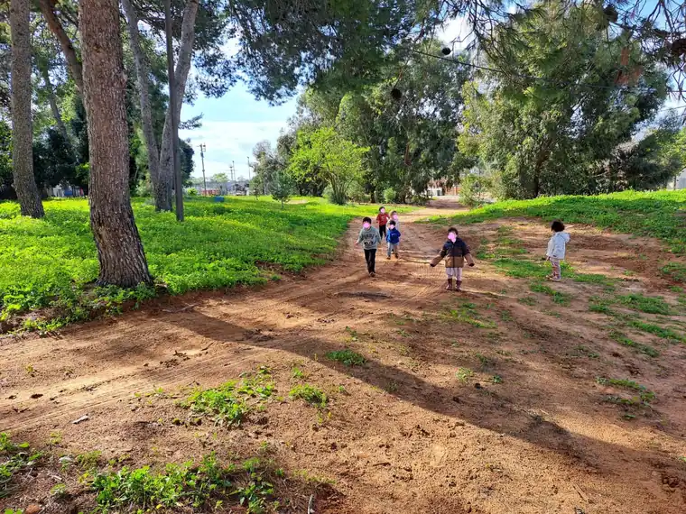 ילדים רצים בשביל עפר בין עצים ודשא